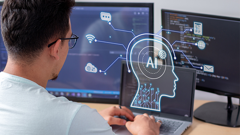 Shot of man's head from behind looking at a laptop screen with an a silhouette of a head above it that reads AI, with different images of things branching out from it